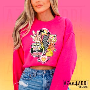 May include: Pink sweatshirt with a graphic design featuring a cartoon jeep, palm trees, a peace sign, a disco ball, lightning bolts, and rubber duckies. The text "Sunset Chapter" is included in the design.
