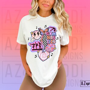 May include: White t-shirt with a graphic design featuring a pink and purple butterfly, a disco ball, a heart with a tie-dye pattern, and the text "Gymnastics".