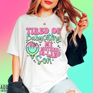 Puede incluir: Camiseta blanca con un gr&aacute;fico rosa y verde que dice "Cansado de cuidar al hijo de mi suegra".