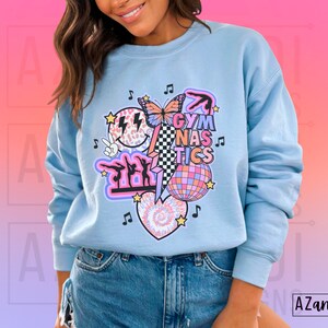 May include: A light blue sweatshirt with a graphic design featuring a butterfly, a disco ball, and the text "Gymnastics".
