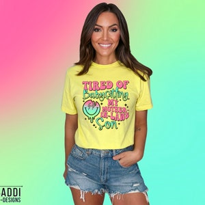 Puede incluir: Una camiseta amarilla con un gr&aacute;fico rosa y azul que dice "Cansado de cuidar al hijo de mi suegra".