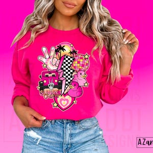 May include: Pink sweatshirt with a graphic design featuring a pink car, a lightning bolt, a peace sign, a disco ball, and rubber ducks. The text "Sunset Cruiser" is included in the design.