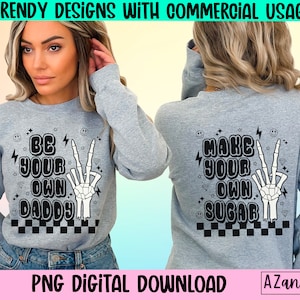 May include: A gray sweatshirt with a black and white graphic design. The design features a skeleton hand making a peace sign, with the text "Be Your Own Daddy" and a checkered pattern.