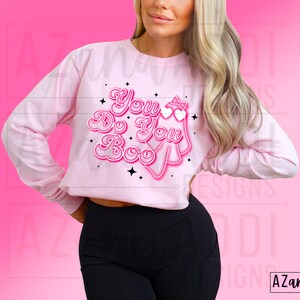 K&ouml;nnte beinhalten: Hellrosa Langarmshirt mit dem Schriftzug "You Do You Boo" in einem Retro-Schriftstil. Das Design beinhaltet einen Geist, Herzen und Sterne. Das Shirt hat einen verk&uuml;rzten Stil.