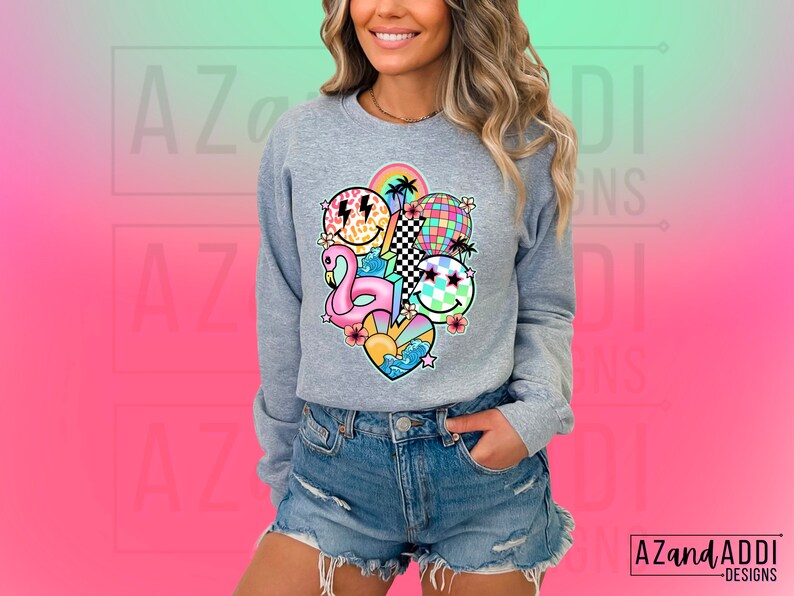 May include: A gray sweatshirt with a colorful graphic print featuring a flamingo, smiley faces, a rainbow, a checkered pattern, and a palm tree. The graphic is centered on the front of the sweatshirt.