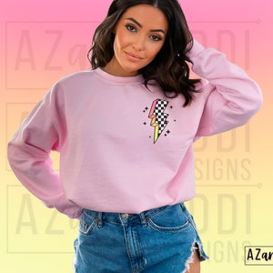 K&ouml;nnte beinhalten: Rosafarbener Pullover mit einem karierten Blitz-Motiv. Das Motiv ist in den Farben Rosa, Gelb und Schwarz gehalten.