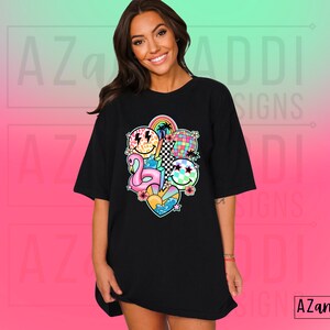 May include: Black oversized t-shirt with a colorful graphic print of a rainbow, a flamingo, a disco ball, and smiley faces. The graphic is centered on the shirt.