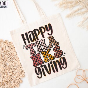 May include: A white canvas tote bag with the text "Happy Thanks Giving" in black and colorful checkered letters. The letters are in a retro style font.
