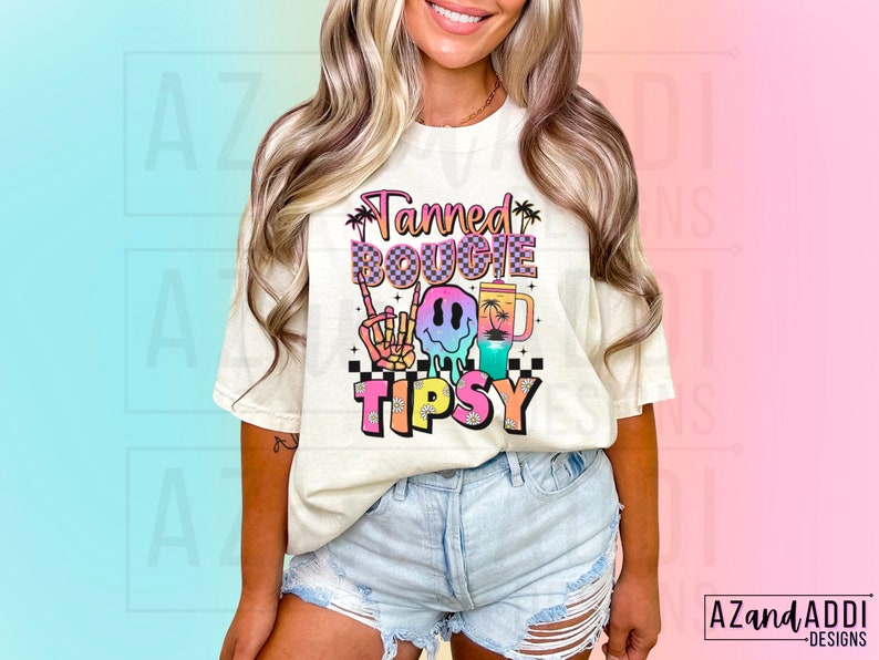 May include: A white t-shirt featuring a colourful graphic design that reads "Tanned Bougie Tipsy". The graphic includes a smiley face wearing sunglasses, a palm tree, and a drink.