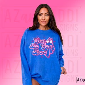 K&ouml;nnte beinhalten: Blaues Sweatshirt mit dem Schriftzug "You Do You Boo" in einem verspielten Retro-Schriftstil. Das Design beinhaltet ein Gespenst mit herzf&ouml;rmiger Brille und Schleife. Das Sweatshirt hat eine einfarbige blaue Farbe.