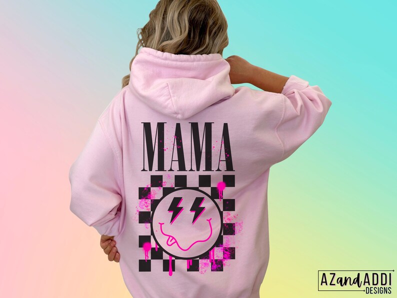 Pu&ograve; includere: Felpa rosa con un designo a scacchi bianco e nero, un'emoticon sorridente rosa con fulmini e la parola "MAMA" in lettere nere.