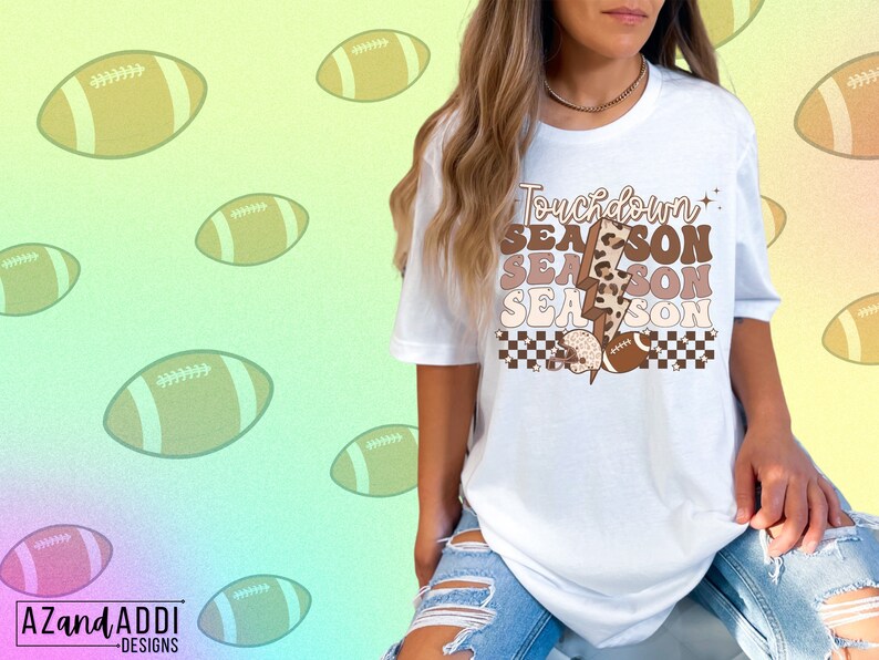 May include: White t-shirt with a brown and white graphic that says "Touchdown Season" with a lightning bolt and football design.