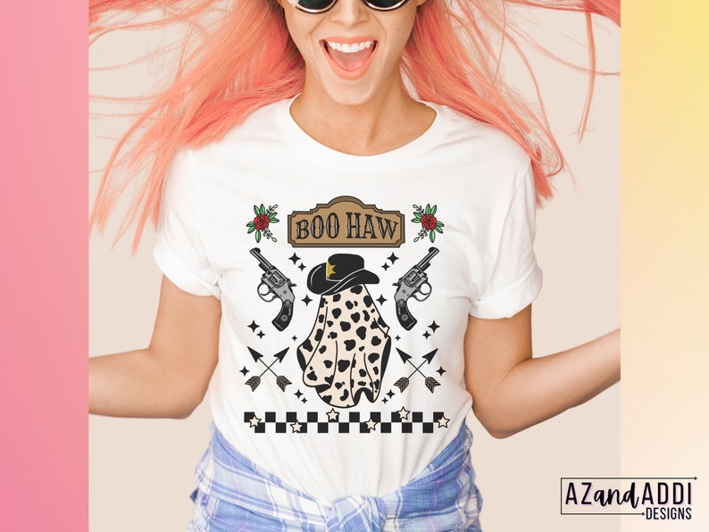 Puede incluir: Camiseta blanca con un fantasma blanco y negro que lleva un sombrero de vaquero y el texto "BOO HAW" en una fuente de estilo vintage. El fantasma est&aacute; rodeado de estrellas, flechas y pistolas.