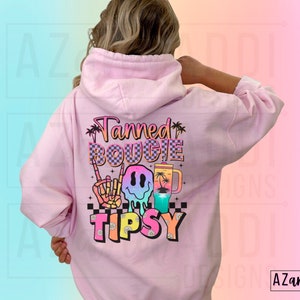 May include: Pink hoodie with a graphic print that says "Tanned Bougie Tipsy" with a smiley face, palm trees, and a drink.