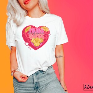 May include: White t-shirt with a pink heart graphic featuring the text "Fries Before Guys" and a cartoon image of french fries.