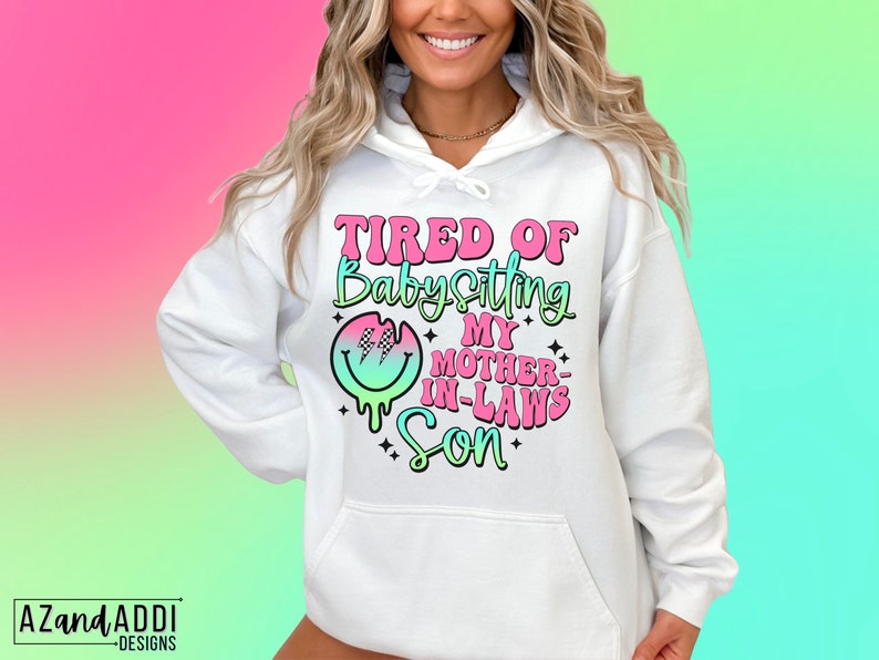 Puede incluir: Sudadera blanca con un gr&aacute;fico rosa, verde y azul que dice "Cansado de cuidar al hijo de mi suegra".
