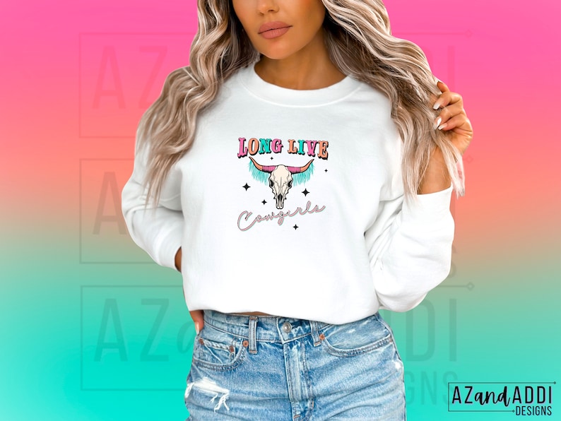 May include: White long-sleeved sweatshirt with a colourful graphic of a cow skull with the text "Long Live Cowgirls".