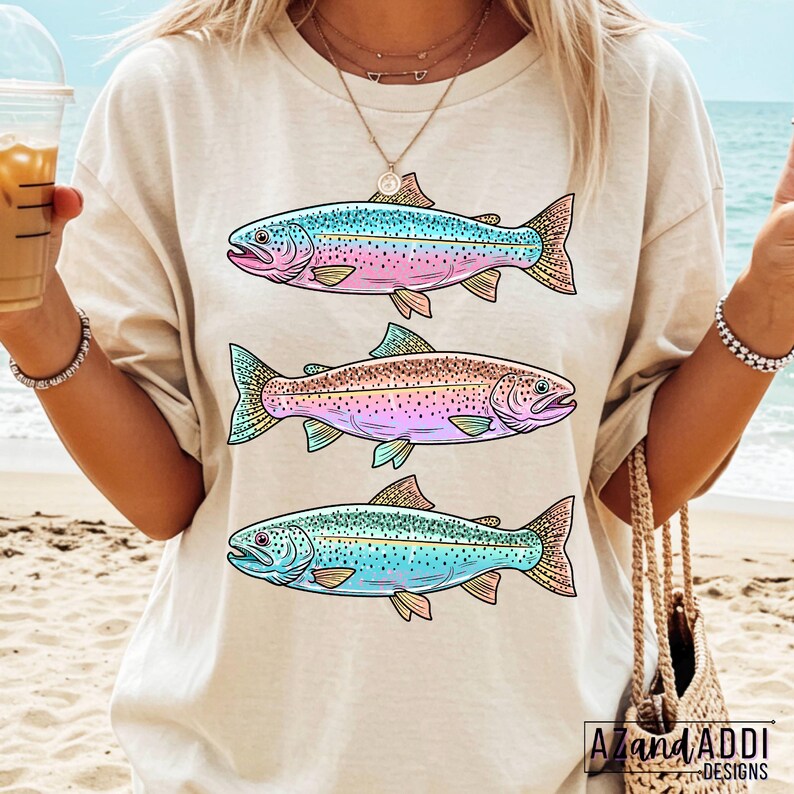 Puede incluir: Camiseta beige con tres ilustraciones de peces coloridos. Cada pez presenta una combinaci&oacute;n de colores &uacute;nica, incluyendo azul, rosa y verde, con dise&ntilde;os detallados de aletas y escamas. La camiseta tiene un corte relajado y es adecuada para uso casual.