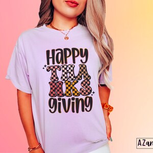 May include: A purple t-shirt with the text "Happy Thanksgiving" in black and brown checkered letters.