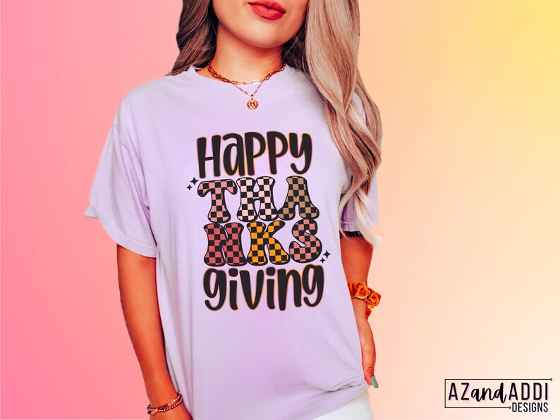 May include: A purple t-shirt with the text "Happy Thanksgiving" in black and brown checkered letters.
