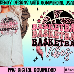 May include: A light gray t-shirt with a basketball graphic and the words "BASKETBALL VIBES" in pink and black. The design includes a basketball with a leopard print pattern, stars, and lightning bolts. The text "PNG DIGITAL DOWNLOAD" is also visible.