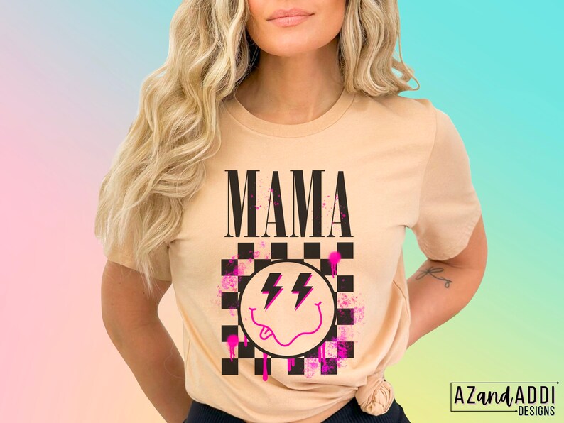 Pu&ograve; includere: Una maglietta color beige con la parola "MAMA" stampata in lettere nere. La maglietta presenta un design a scacchi bianco e nero con un'emoticon sorridente rosa e un grafico a forma di fulmine.