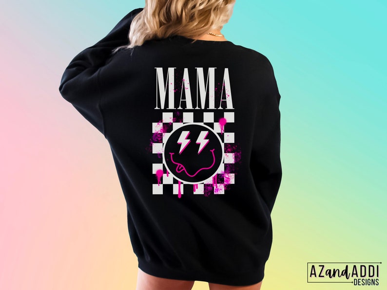 Pu&ograve; includere: Felpa nera con un design a scacchi rosa e bianco, un'emoticon sorridente rosa con fulmini e la parola "MAMA" in lettere bianche.