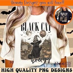 May include: A cream-colored t-shirt featuring a graphic of a black cat wearing a checkered witch hat in a pumpkin patch. The text reads BLACK CAT ENERGY. The design includes a full moon, a jack-o'-lantern balloon, and a wooden sign labeled PUMPKIN PATCH.