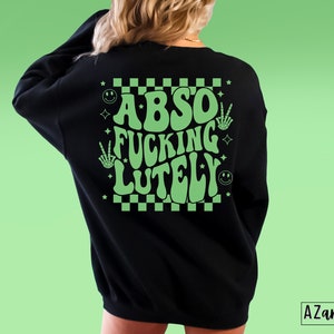 May include: Black sweatshirt with a green checkered pattern and the text "ABSO FUCKING LUTELY" in a retro font.