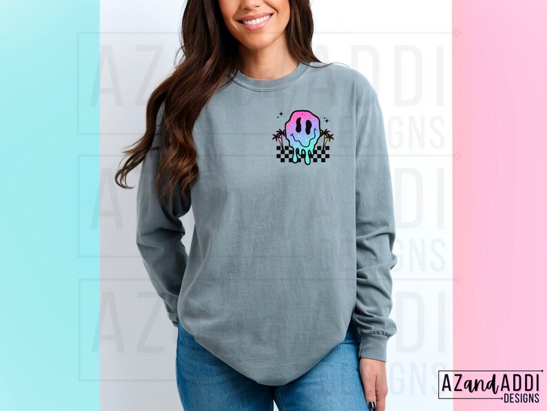 May include: A grey long-sleeved t-shirt with a colourful dripping smiley face graphic and palm trees on a chequered background.