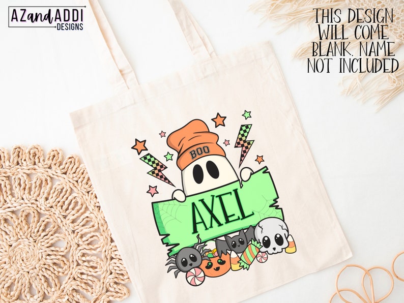 K&ouml;nnte beinhalten: Eine cremefarbene Tragetasche mit einem Halloween-Design. Sie zeigt einen Geist mit einer orangefarbenen M&uuml;tze, der ein gr&uuml;nes Schild mit dem Namen "AXEL" h&auml;lt. Das Design umfasst Sterne, Blitze und Halloween-Leckereien. Der Text auf der Tasche lautet "THIS DESIGN WILL COME BLANK. NAME NOT INCLUDED."