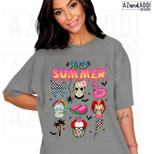 May include: A gray t-shirt with the words "Hello Summer" in pink and blue, featuring various summer-themed graphics. The graphics include a checkered bow, a Jason Voorhees mask, a pink flamingo float, and a watermelon slice.