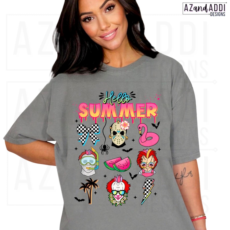 May include: A gray t-shirt with the words "Hello Summer" in pink and blue, featuring various summer-themed graphics. The graphics include a checkered bow, a Jason Voorhees mask, a pink flamingo float, and a watermelon slice.