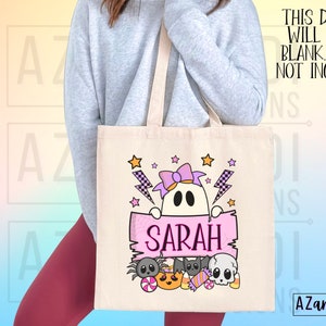 K&ouml;nnte beinhalten: Eine beigefarbene Canvas-Tragetasche mit einem Halloween-Motiv. Das Design zeigt einen Geist mit einer lila Schleife, Sternen und Blitzen. Der Name "SARAH" ist auf einem rosa Banner zu sehen, darunter Halloween-Figuren. Der Text "THIS DESIGN WILL COME BLANK. NAME NOT INCLUDED" ist ebenfalls sichtbar.