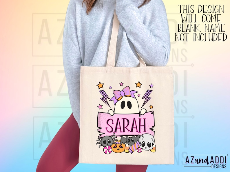 K&ouml;nnte beinhalten: Eine beigefarbene Canvas-Tragetasche mit einem Halloween-Motiv. Das Design zeigt einen Geist mit einer lila Schleife, Sternen und Blitzen. Der Name "SARAH" ist auf einem rosa Banner zu sehen, darunter Halloween-Figuren. Der Text "THIS DESIGN WILL COME BLANK. NAME NOT INCLUDED" ist ebenfalls sichtbar.
