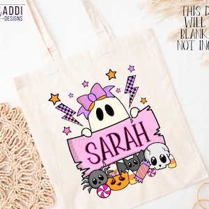 K&ouml;nnte beinhalten: Eine cremefarbene Tragetasche mit einem Halloween-Design. Das Design zeigt einen Geist, der ein rosa Schild mit dem Namen "SARAH" h&auml;lt, umgeben von Sternen, einer Spinne, S&uuml;&szlig;igkeiten und einer Fledermaus. Der Text "THIS DESIGN WILL COME BLANK. NAME NOT INCLUDED" ist ebenfalls sichtbar.