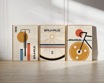 Peut inclure: Un ensemble de trois affiches encadrées présentant des graphismes de bicyclette inspirés du Bauhaus. Les impressions affichent des formes géométriques, des lignes et le texte 'BAUHAUS' et '1919' dans une palette de crème, noir, orange et bleu.