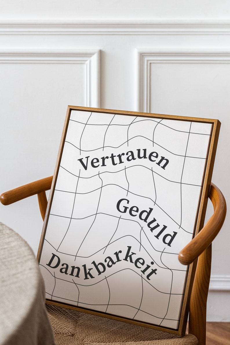 May include: A framed print with a white background and black grid pattern. The words "Vertrauen", "Geduld", and "Dankbarkeit" are written in black on the print.