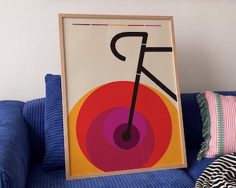 May include: A framed vertical poster featuring a minimalist black line drawing of a bicycle frame positioned above a series of overlapping concentric circles in shades of red, orange, and purple, set against a light cream background.