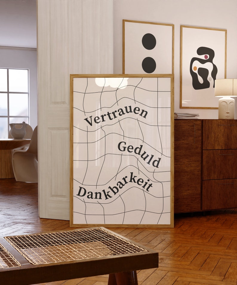 May include: A framed print with a white background and black grid pattern. The words "Vertrauen", "Geduld", and "Dankbarkeit" are written in black on the grid.