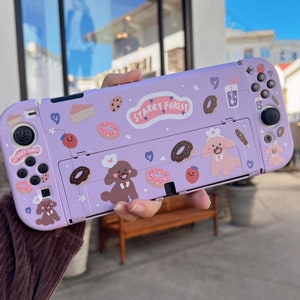 May include: Purple Nintendo Switch case with a cute cartoon design featuring dogs, donuts, and the text "Starry Forest".