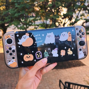 May include: A black Nintendo Switch console with a Halloween-themed design. The console is decorated with stickers of ghosts, pumpkins, and other spooky characters. The text "Last Five Minutes" is written on the console.