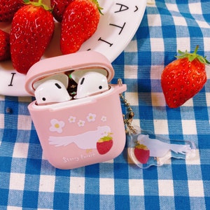 Puede incluir: Una funda rosa para Airpods con un dise&ntilde;o de p&aacute;jaro blanco y el texto "Starry Forest". La funda tiene un peque&ntilde;o charm de fresa.
