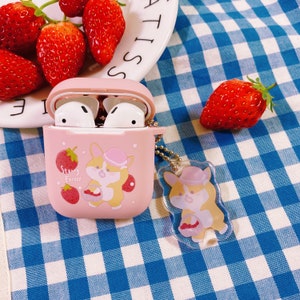 Puede incluir: Funda rosa para Airpods con un dise&ntilde;o de corgi de dibujos animados y el texto "Starry Forest". La funda est&aacute; sobre una superficie a cuadros azules y blancos con fresas.