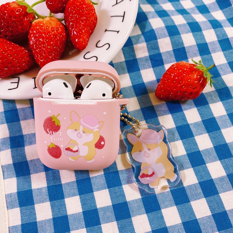 Puede incluir: Funda rosa para Airpods con un dise&ntilde;o de corgi de dibujos animados y el texto "Starry Forest". La funda est&aacute; sobre una superficie a cuadros azules y blancos con fresas.