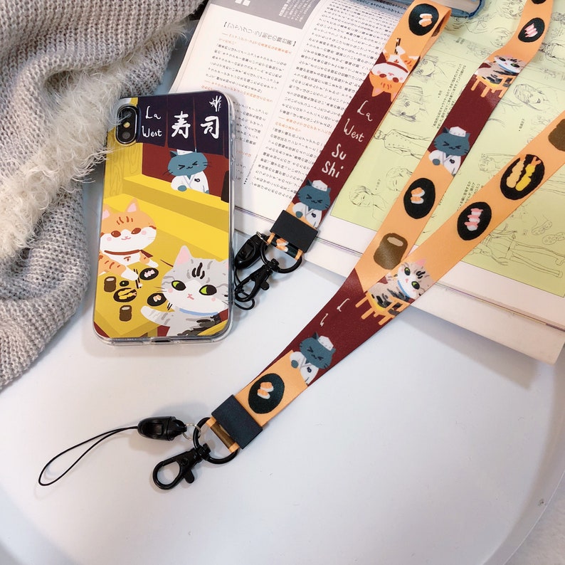 Może przedstawiać: Etui na telefon z ż&oacute;łtym tłem i kresk&oacute;wkową grafiką kot&oacute;w jedzących sushi. Etui jest przymocowane do ż&oacute;łto-brązowego paska do telefonu z czarną klamrą. Pasek ma kresk&oacute;wkową grafikę kot&oacute;w jedzących sushi.