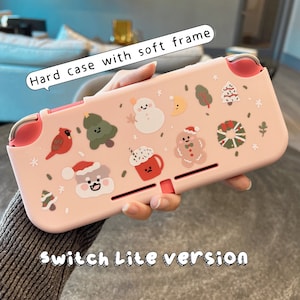 K&ouml;nnte beinhalten: Rosa Nintendo Switch Lite H&uuml;lle mit weichem Rahmen. Die H&uuml;lle zeigt ein Winterferien-Thema mit Illustrationen von einem Schneemann, einem Lebkuchenmann und Weihnachtsb&auml;umen.