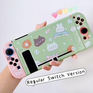 May include: A green and pink Nintendo Switch case with a baseball theme. The case features a cartoon cat, rabbit, and a baseball bat. The text "Championship" is printed on the case.