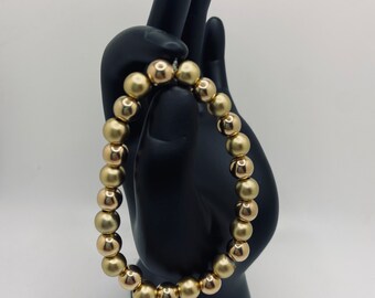 May include: A gold beaded bracelet with round beads.