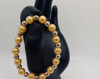 May include: A gold and rose gold beaded bracelet with alternating large and small beads.